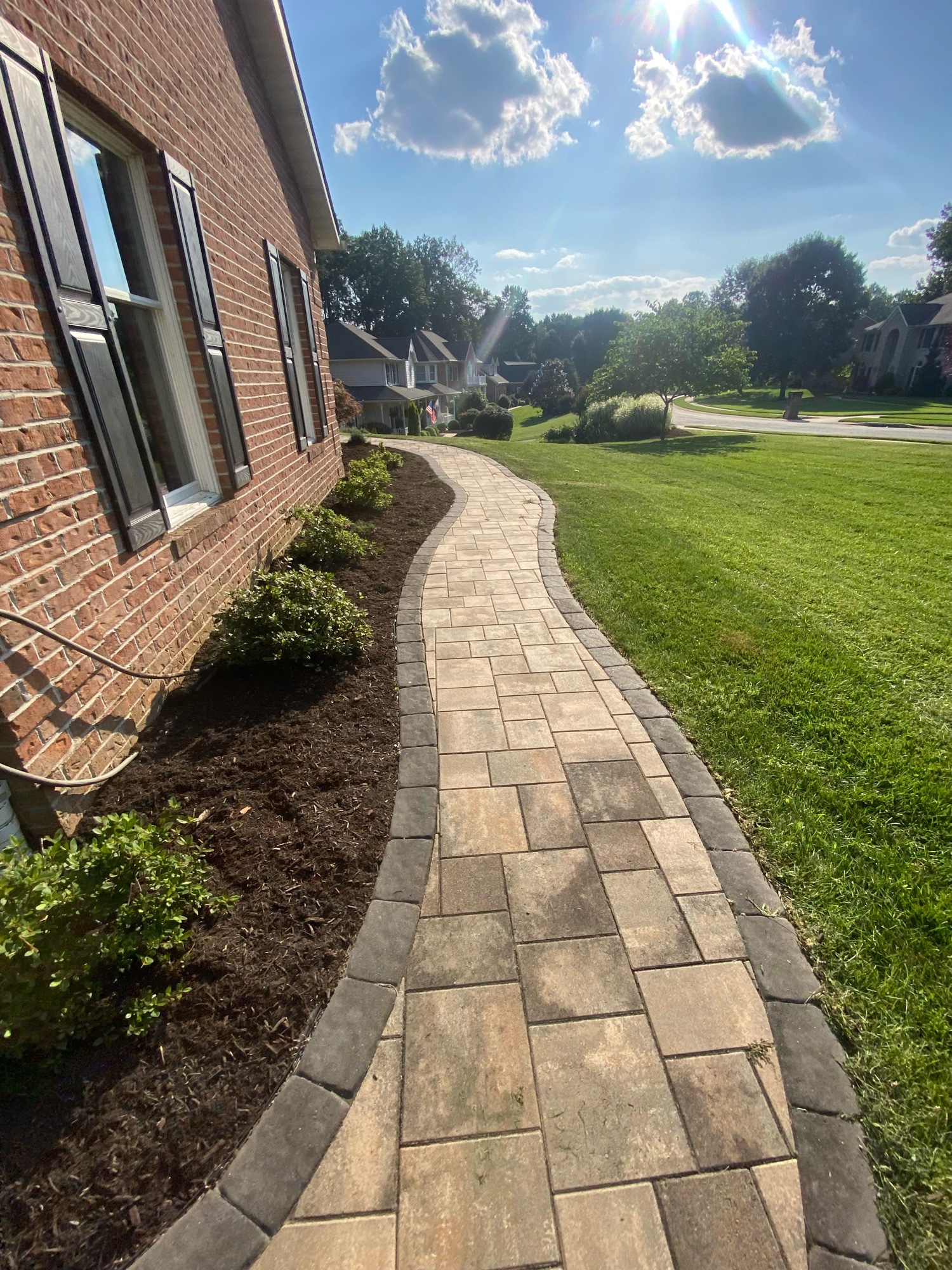 Curved retaining wall with fresh mulch and green lawn